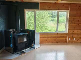 Cozy living space featuring a modern black wood-burning stove with a sleek metal hearth and protective screen.
