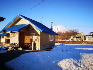 Discover this charming home featuring a vibrant blue metal roof and warm tan siding, set against a backdrop of a majestic snow-capped mountain.