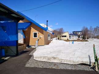This charming wooden house features a vibrant blue roof and is situated in a picturesque snowy landscape.