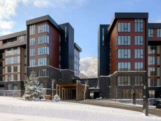 Experience luxury mountain living in this stunning modern hotel, nestled amidst a serene winter landscape.
