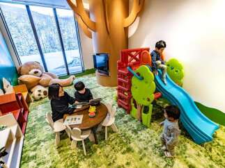 This inviting play area features a cozy reading nook with a large teddy bear and a table for children's activities.