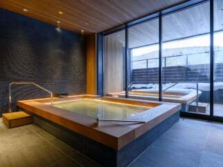 Experience ultimate relaxation in this luxurious indoor hot spring bath, featuring a spacious wooden-decked tub with ambient lighting.