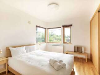 Experience serene living in this beautifully appointed bedroom, featuring a comfortable queen-size bed dressed in crisp white linens.