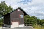 Discover this charming two-story home featuring a dark wood exterior and a durable green roof.