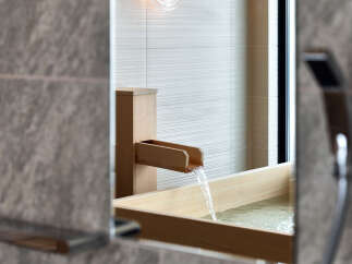 Experience tranquility in this modern bathroom featuring a luxurious wooden soaking tub, where water gracefully flows from a sleek wooden spout.