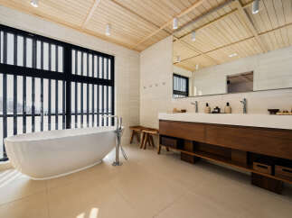 Experience modern luxury in this stunning bathroom featuring a freestanding soaking tub with a sleek chrome faucet, perfect for unwinding.