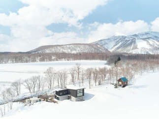 Discover this stunning modern home nestled in a serene winter landscape, offering breathtaking mountain views.