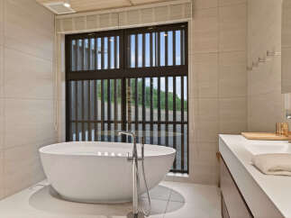 Experience ultimate relaxation in this luxurious bathroom, featuring a freestanding soaking tub with a modern floor-mounted faucet.
