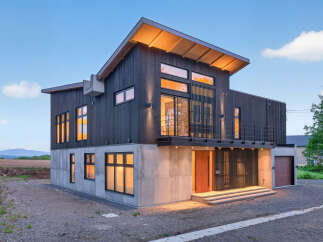 Discover modern living in this striking architectural home, featuring a unique blend of dark wood siding and exposed concrete.