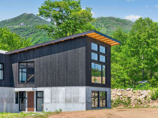 Discover modern mountain living in this stunning architectural home, featuring a striking dark wood exterior and a concrete foundation.