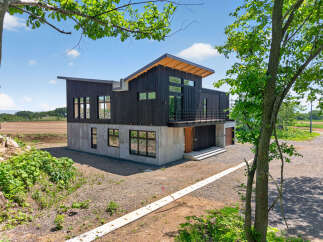 Discover modern living in this striking architectural home featuring a dark wood exterior and a concrete base.