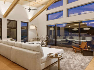 Experience modern luxury in this stunning living room, featuring a vaulted ceiling with exposed wooden beams and a sleek ceiling fan.