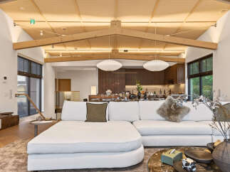Experience modern living in this stunning open-concept space, featuring a vaulted wood-beamed ceiling and abundant natural light.