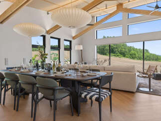 Experience modern luxury in this stunning dining area, featuring a large wooden table set for a feast and surrounded by elegant chairs.