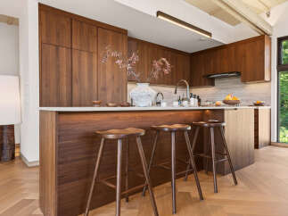 Experience modern luxury in this stunning kitchen featuring rich walnut cabinetry and a sleek waterfall island.