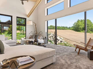 Experience modern living with expansive floor-to-ceiling windows that frame breathtaking views of rolling fields and lush greenery.
