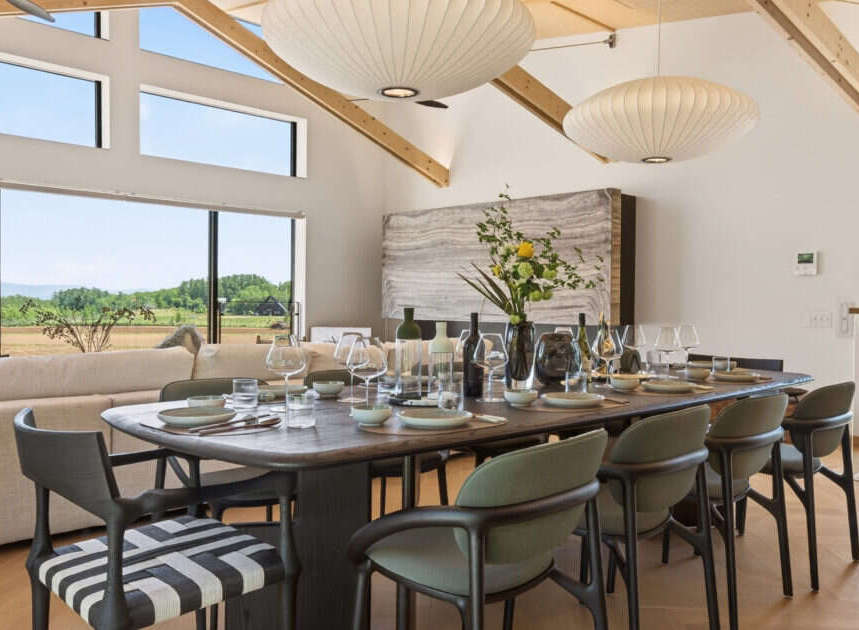 Experience elegant dining in this spacious room, featuring a large wooden table set for a feast and surrounded by stylish chairs.