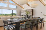 Experience elegant dining in this spacious room, featuring a large wooden table set for a feast and surrounded by stylish chairs.