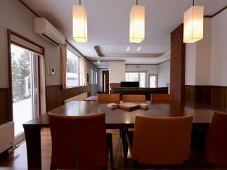 This spacious dining area features a large wooden table surrounded by comfortable orange chairs, perfect for family gatherings.
