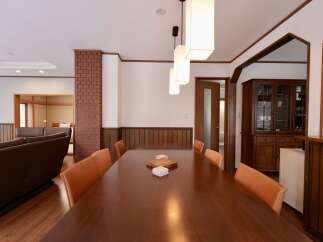 This spacious dining area features a large, polished wooden table surrounded by elegant orange leather chairs, perfect for hosting gatherings.
