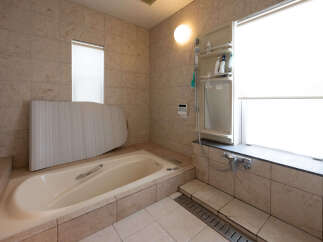 This spacious bathroom features a large, built-in bathtub with a sleek chrome handle, perfect for relaxing soaks.