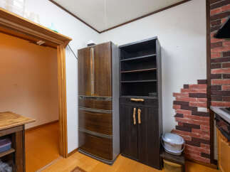 Discover a charming kitchen space featuring a classic wooden refrigerator and a tall, dark wood cabinet with open shelving and lower cabinets.
