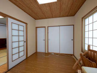 Discover the serene ambiance of this Japanese-style room, featuring traditional shoji screens and a tatami mat area visible through an open doorway.
