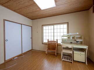 Discover this charming room featuring a traditional Japanese-style sliding door, a large window with a grid pattern, and a wooden desk with a hutch and chair.