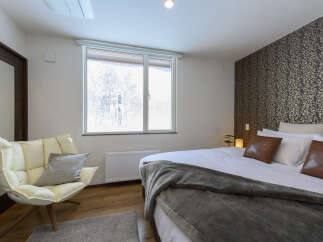 Experience comfort and style in this beautifully appointed bedroom, featuring a plush cream armchair perfect for relaxation.