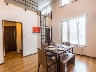 Experience modern living in this spacious dining area featuring a large wooden table set for a meal, complemented by a cozy bench and chairs.