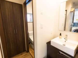 Discover modern living with this well-appointed bathroom featuring a sleek vanity and sink, complemented by a convenient in-unit washer and dryer visible in the mirror's reflection.
