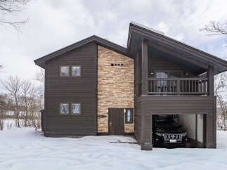 Experience luxury mountain living in this stunning modern chalet, featuring a striking stone accent wall and rich dark wood siding.