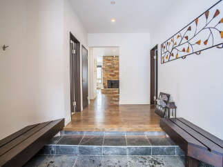 Step into a welcoming entryway featuring a split-level design with dark stone tile leading to polished hardwood floors.