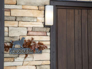 Welcome to Cuddlesville, a charming property featuring a rustic stone facade complemented by a warm wooden door.