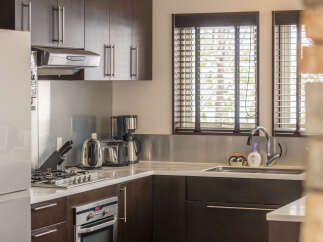 This modern kitchen boasts sleek dark wood cabinetry and a stainless steel backsplash, complemented by a gas stovetop and a built-in oven.