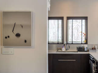 This modern kitchen features sleek dark cabinetry and a spacious countertop, perfect for meal preparation.