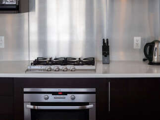 This modern kitchen features a sleek stainless steel backsplash, a built-in gas stovetop, and a matching oven.