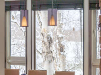 Experience cozy winter dining in this elegant home, featuring a spacious dining table set for tea with a view of snow-covered trees.