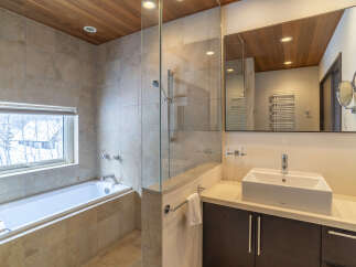 Experience luxury and relaxation in this stunning bathroom featuring a deep soaking tub with a view of the winter landscape.