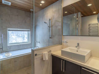 Experience luxury in this modern bathroom featuring a deep soaking tub with a scenic window view, perfect for unwinding.