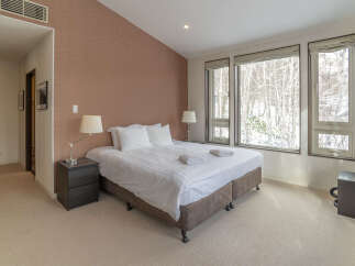 Experience cozy winter living in this charming bedroom, featuring a comfortable queen-size bed adorned with crisp white linens and plush pillows.
