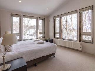 Experience serene winter views from this inviting bedroom, featuring a comfortable king-sized bed adorned with crisp white linens.