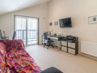 This spacious room features a comfortable sofa with a vibrant floral throw, perfect for relaxing.