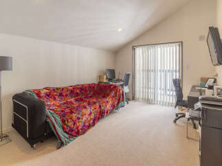 This spacious room features a comfortable sofa adorned with a vibrant floral throw, perfect for relaxation.