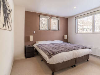 Experience cozy comfort in this inviting bedroom, featuring a plush king-sized bed adorned with a stylish patterned throw.