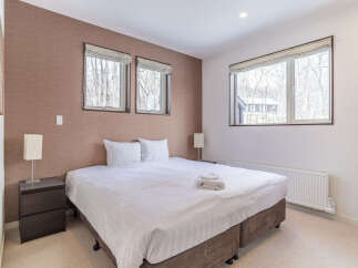 Experience comfort and style in this beautifully appointed bedroom, featuring a plush king-sized bed with crisp white linens and two matching pillows.