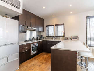 Experience modern living in this sleek kitchen featuring dark wood cabinetry and a spacious white quartz countertop island.