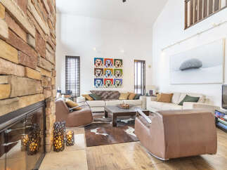 Experience luxury living in this stunning great room, featuring a dramatic floor-to-ceiling stone fireplace and soaring vaulted ceilings.