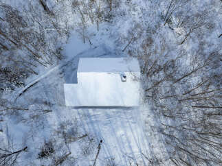 Experience serene winter living in this secluded home, nestled amidst a snow-covered forest.