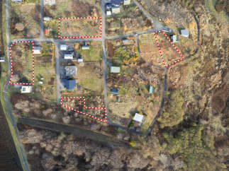 Explore this aerial view of a rural property featuring multiple parcels of land, some with existing structures and others cleared for development.